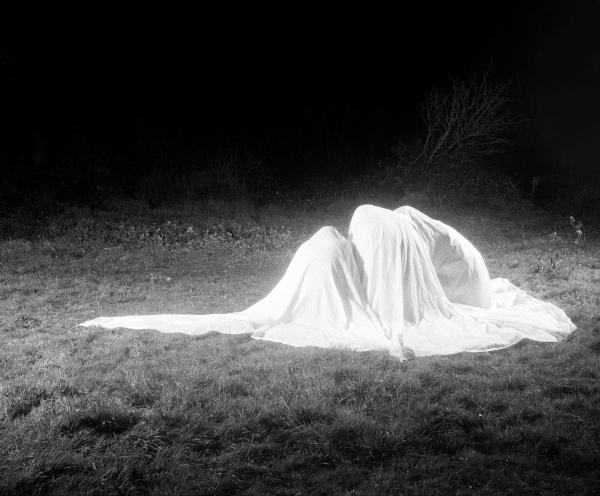 people beneath a sheet in a forest 